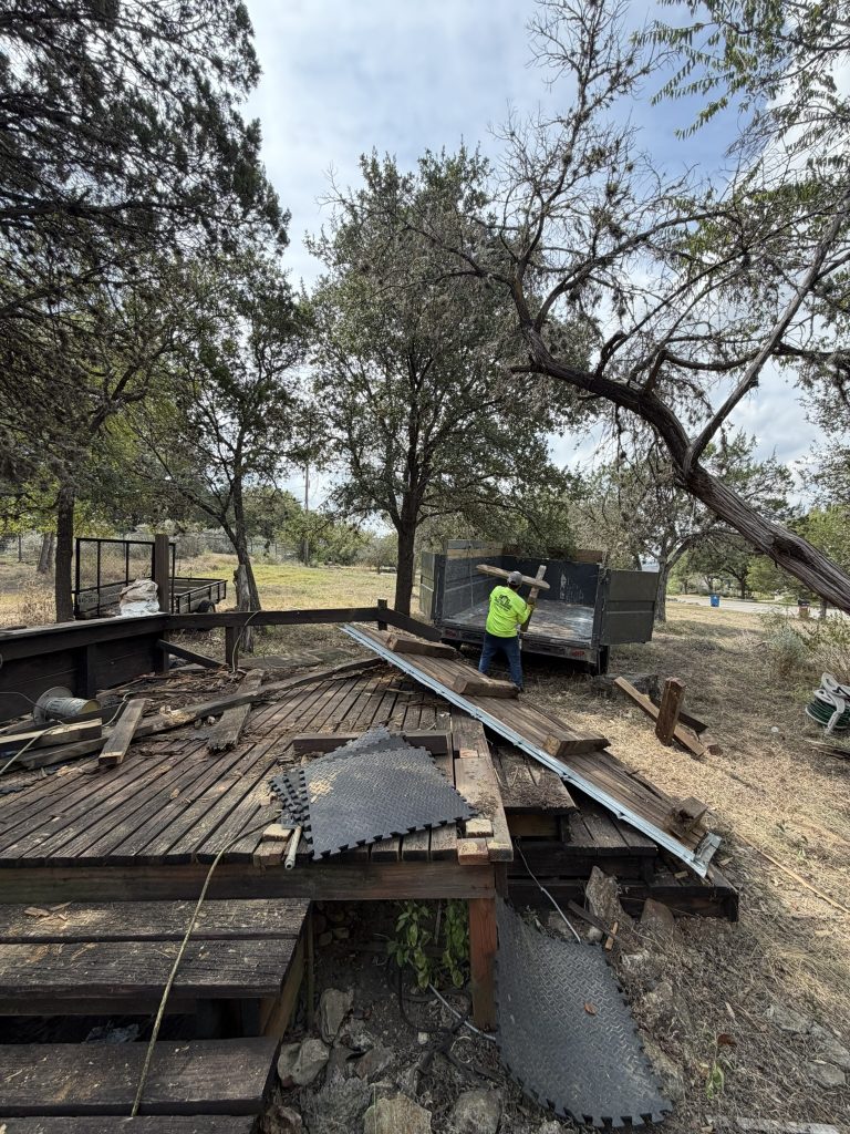 Alamo Bros crew member loading a removed wooden deck beam into a debris trailer